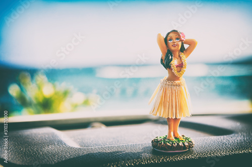 Hawaii hula dancer girl doll on dashboard of car road trip - summer vacation travel dancing woman at ocean beach. Tourism and travel freedom concept. photo