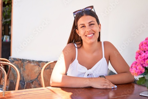 Young beautiful woman sitting at restaurant enjoying summer vacation
