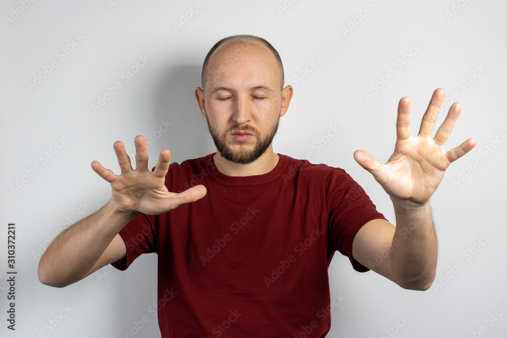 Young man with closed eyes and outstretched arms on a light background. Concept of looking for something with eyes closed, poor eyesight, blindness, closing eyes for something Young man with closed eyes and outstretched arms on a light background. Concept of looking for something with eyes closed, poor eyesight, blindness, closing eyes for something