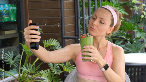 Sport, Fitness, Lifestyle, Technology And People Concept - Young Woman Using Smartphone Taking Selfie With Green Smoothie
