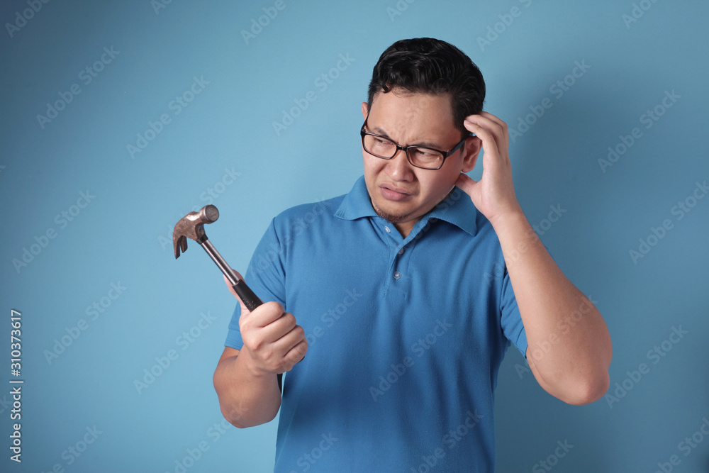 Confused skill-less man looking at hammer Confused skill-less man looking at hammer