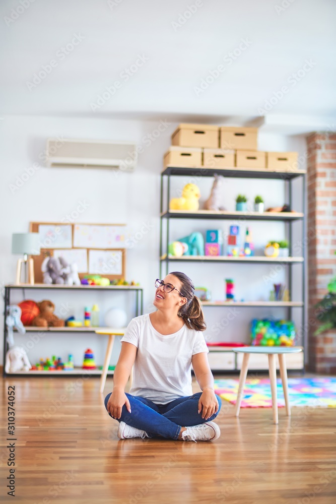 Young beautiful teacher wearing glasses sitting at kindergarten Young beautiful teacher wearing glasses sitting at kindergarten