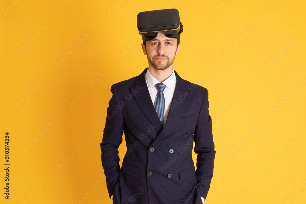 A man in a suit with a tie Handsome looking face with beard In the business man look Wearing a VR device on his head in a yellow background A man in a suit with a tie Handsome looking face with beard In the business man look Wearing a VR device on his head in a yellow background