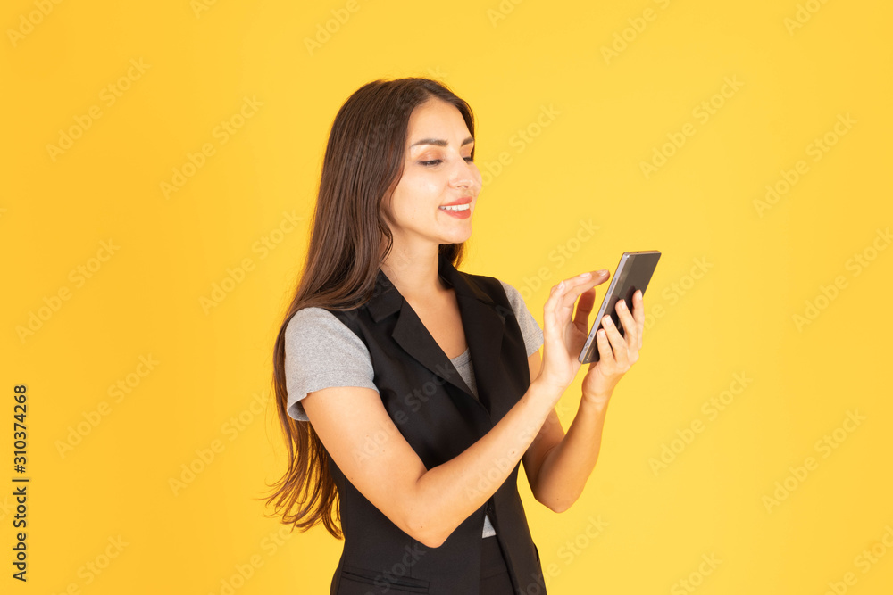 A woman standing and playing with a mobile phone In the yellow background A woman standing and playing with a mobile phone In the yellow background