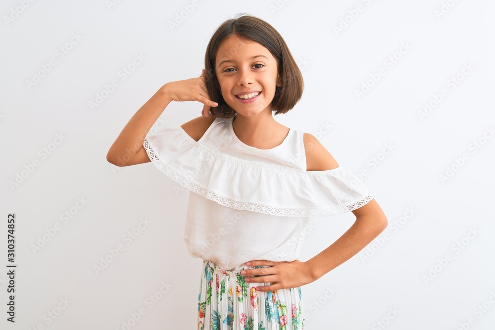 Young beautiful child girl wearing casual dress standing over isolated white background smiling doing phone gesture with hand and fingers like talking on the telephone. Communicating concepts. Young beautiful child girl wearing casual dress standing over isolated white background smiling doing phone gesture with hand and fingers like talking on the telephone. Communicating concepts.