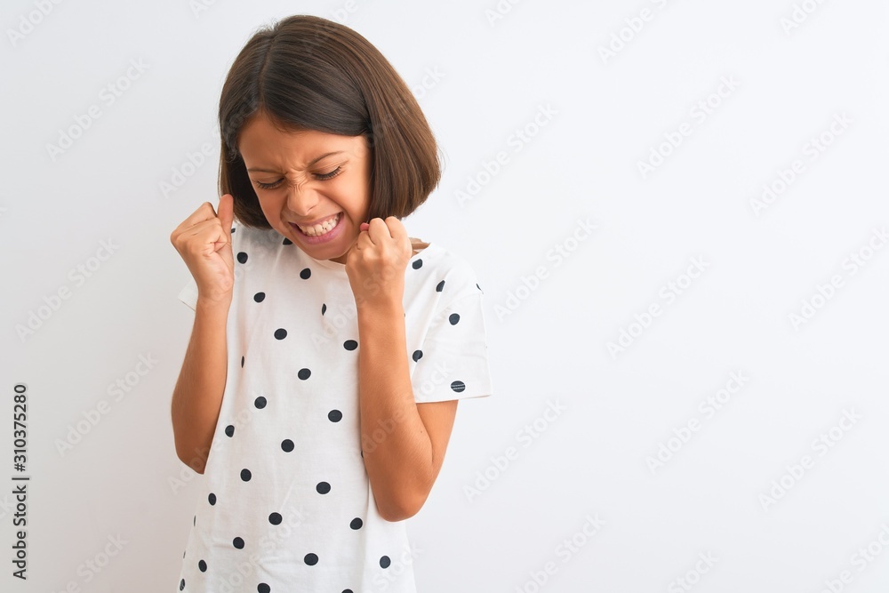 Young beautiful child girl wearing casual t-shirt standing over isolated white background very happy and excited doing winner gesture with arms raised, smiling and screaming for success. Celebration Young beautiful child girl wearing casual t-shirt standing over isolated white background very happy and excited doing winner gesture with arms raised, smiling and screaming for success. Celebration