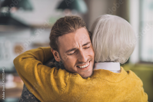 Young handsome man in camouflage hugging his mom