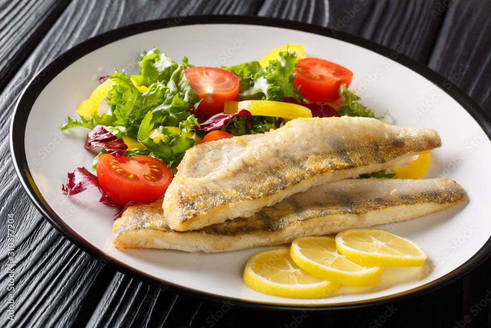 Freshwater fish fillet of zander fried with fresh vegetables and lemon close-up in a plate. horizontal Freshwater fish fillet of zander fried with fresh vegetables and lemon close-up in a plate. horizontal