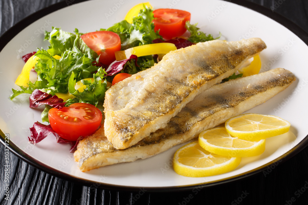 Tasty fried zander fillet with fresh vegetable salad close-up in a plate on the table. horizontal Tasty fried zander fillet with fresh vegetable salad close-up in a plate on the table. horizontal