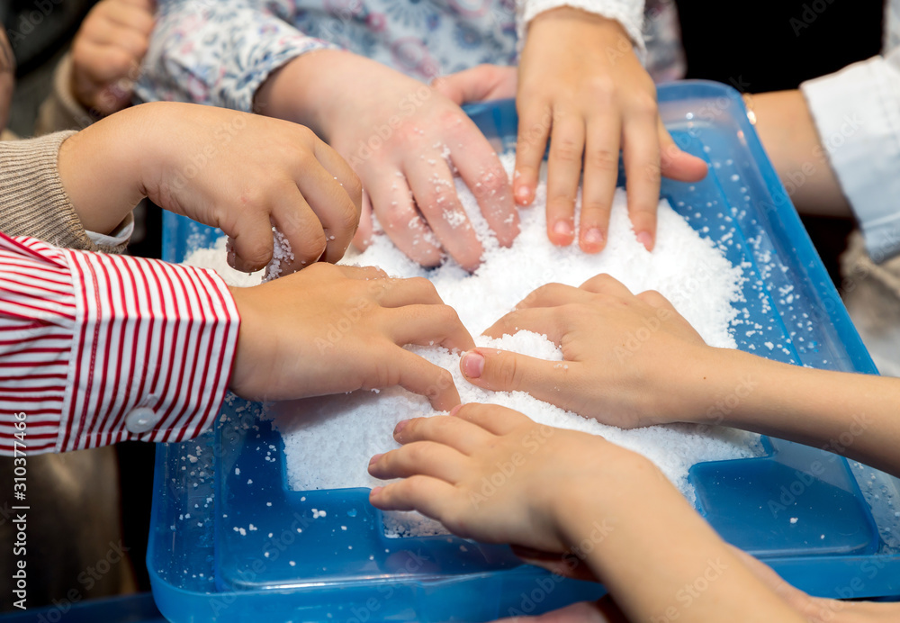 Fototapeta premium Children touch and play with artificial snow during the holiday. Many children's hands