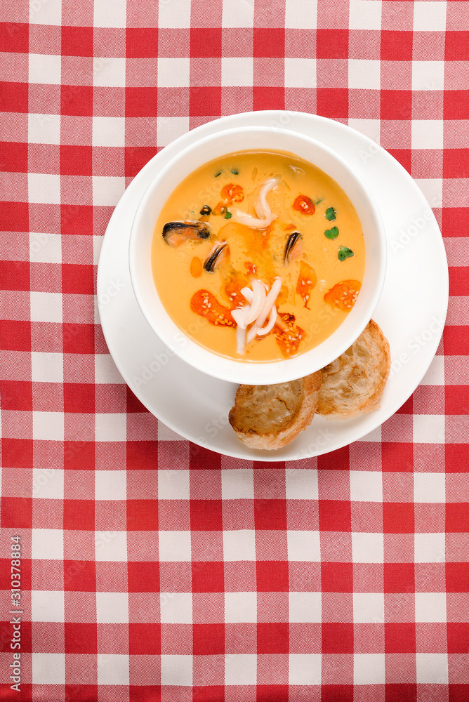 Tomato soup with mussel and pasta in a bowl on plaid tablecloth. Italian cioppino soup with bread. Top view copy space Tomato soup with mussel and pasta in a bowl on plaid tablecloth. Italian cioppino soup with bread. Top view copy space