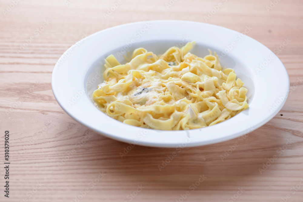 Italian homemade pasta with meat and vegetables served on white plate on grey wooden background.