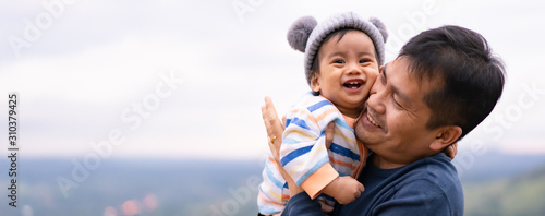 Asian father is playing with little baby boy with happiness moment on the background of nature , concept of trust love and bonding in family life.