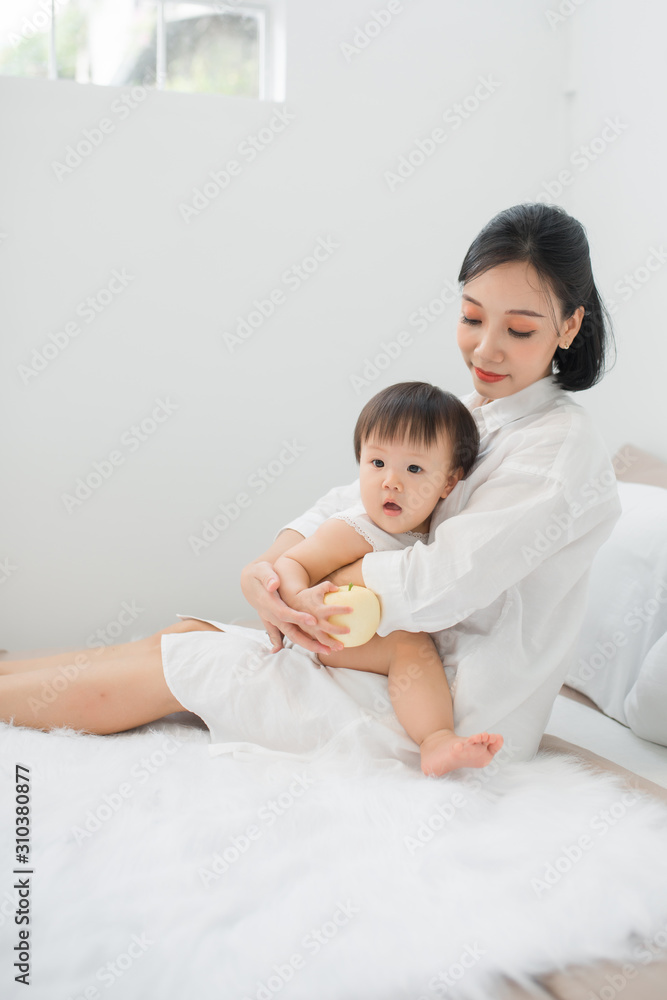Young mother playing with her baby in bedroom at home Young mother playing with her baby in bedroom at home