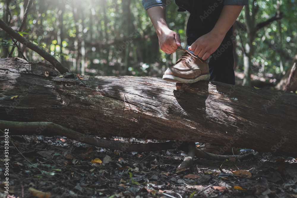 Man is tying shoelace while preparing for hiking in the forest. Man is tying shoelace while preparing for hiking in the forest.