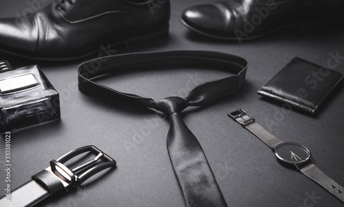 Tie, wristwatch, perfume, belt, wallet, shoes on the black background. Men accessories