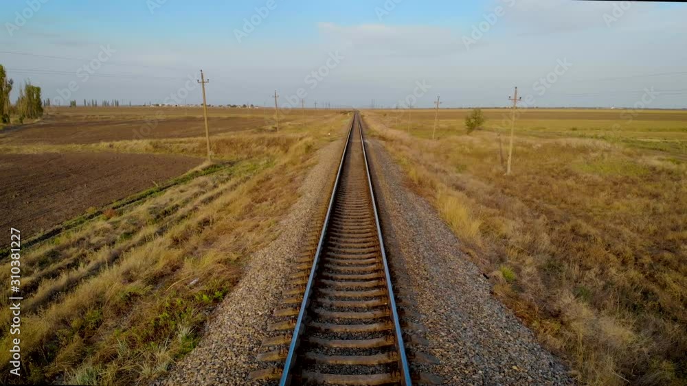 Aerial view of overview with locomotive on railway line tracks in motion near countryside. Drone shoots video rails near farm fields concept of transportation infrastructure travel industry Aerial view of overview with locomotive on railway line tracks in motion near countryside. Drone shoots video rails near farm fields concept of transportation infrastructure travel industry
