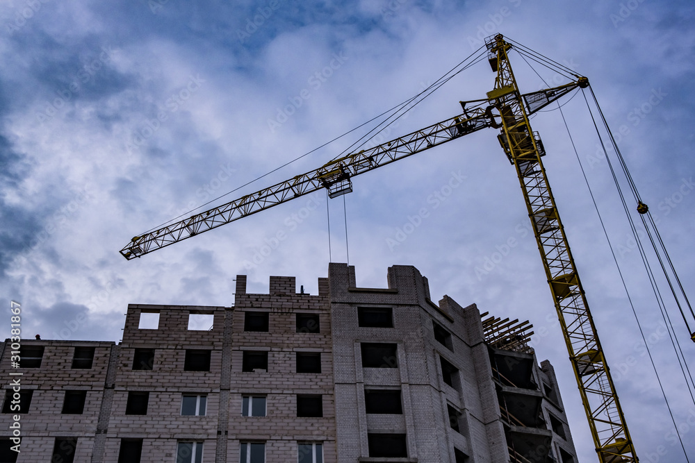 Tower cranes and unfinished multi-storey high buildings under construction site in the evening with dramatic colorful cloud background Tower cranes and unfinished multi-storey high buildings under construction site in the evening with dramatic colorful cloud background