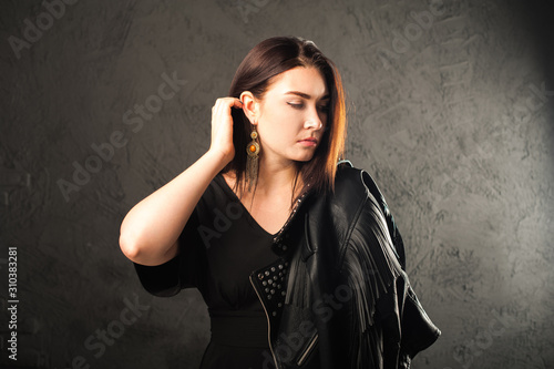 Closeup portrait of a woman on a black background. Girl in a black leather jacket and copy space. Beauty portrait of a woman in black overalls.