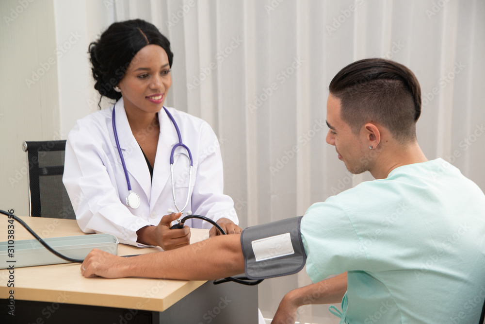 Fototapeta premium Afican female Doctor measuring Caucasian male patient blood with pressure Measuring Patient.