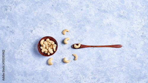 cashew nut in a wooden bowl whith wooden spoon on a blue and white background top view