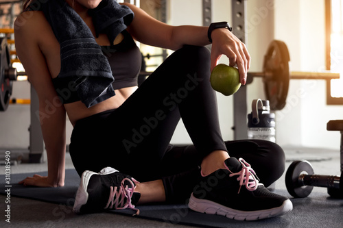 Woman holding apple after fitness exercise at gym. Healthy and lifestyle concept.