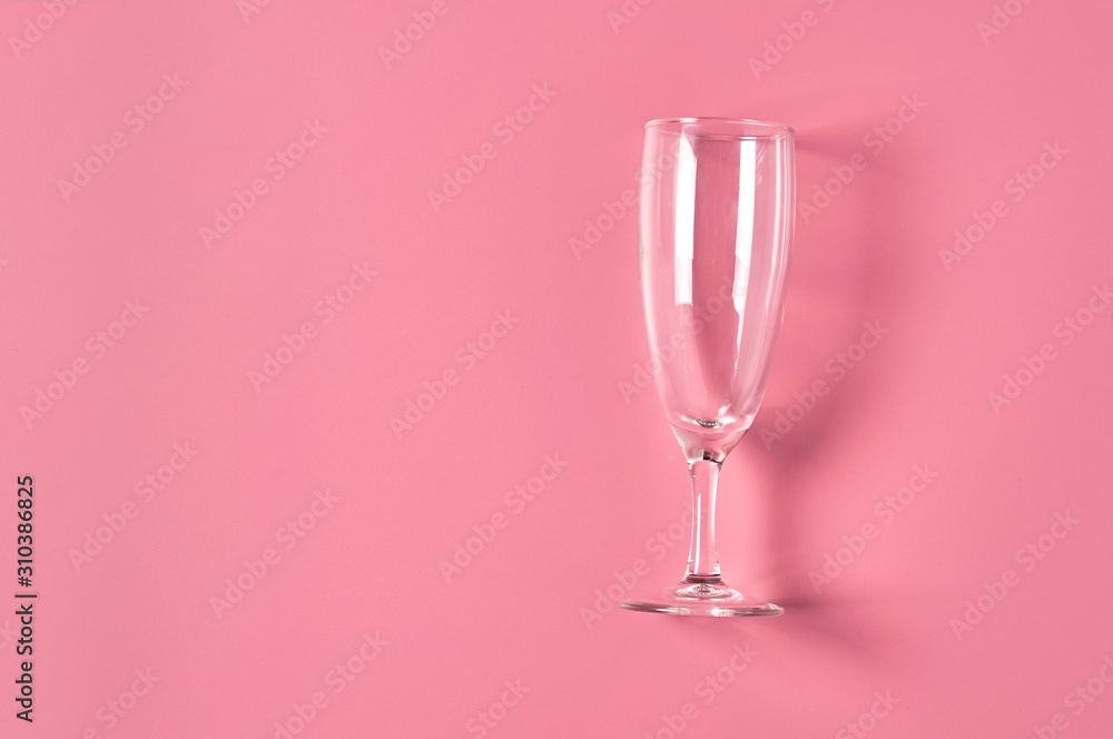 Single empty glass for champagne lies on pink table on kitchen. Concept of celebrating. Space for text. Top view Single empty glass for champagne lies on pink table on kitchen. Concept of celebrating. Space for text. Top view
