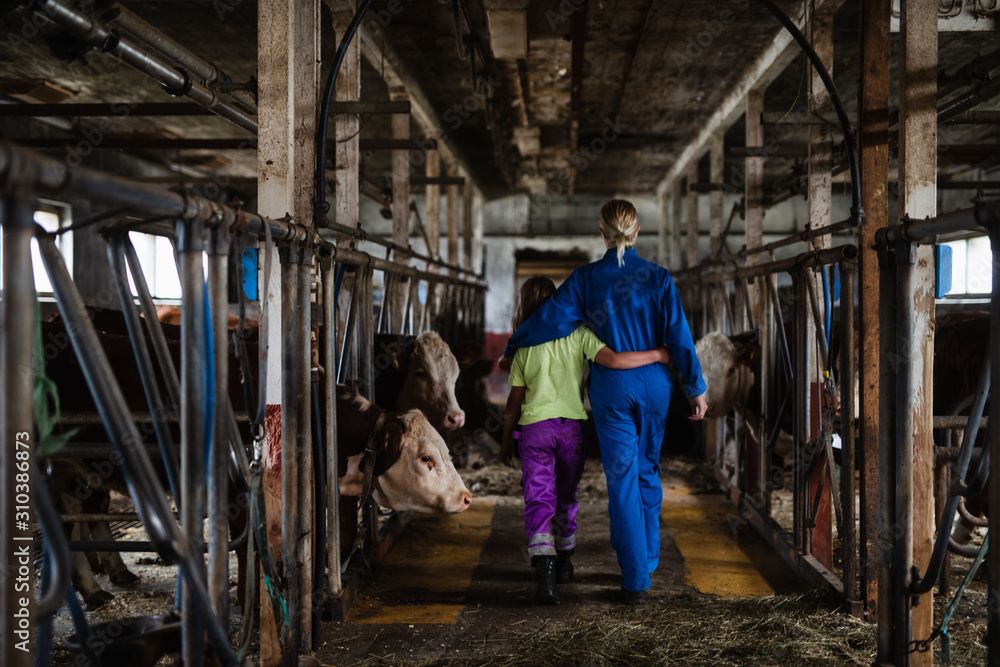 Woman with daughter in cowshed Woman with daughter in cowshed