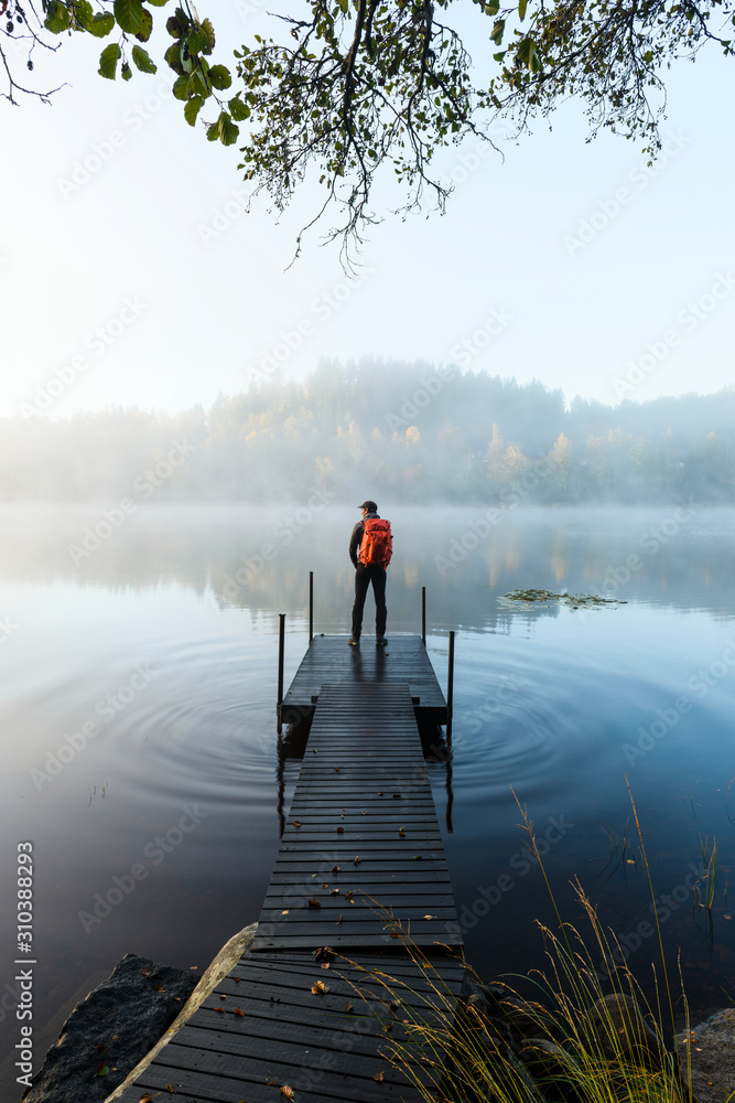 Man on pier in lake in morning fog Man on pier in lake in morning fog
