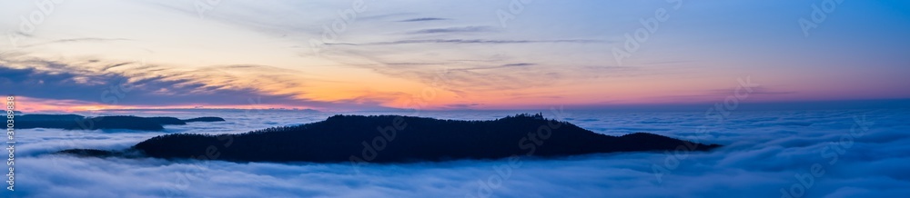Germany, XXL panorama aerial view above fog clouds in valley of swabian jura nature landscape at sunset near stuttgart on mountain breitenstein with view to castle teck