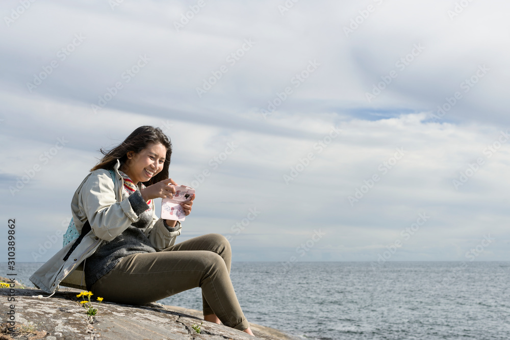 Teenage girl with cell phone sitting on sea coast Teenage girl with cell phone sitting on sea coast
