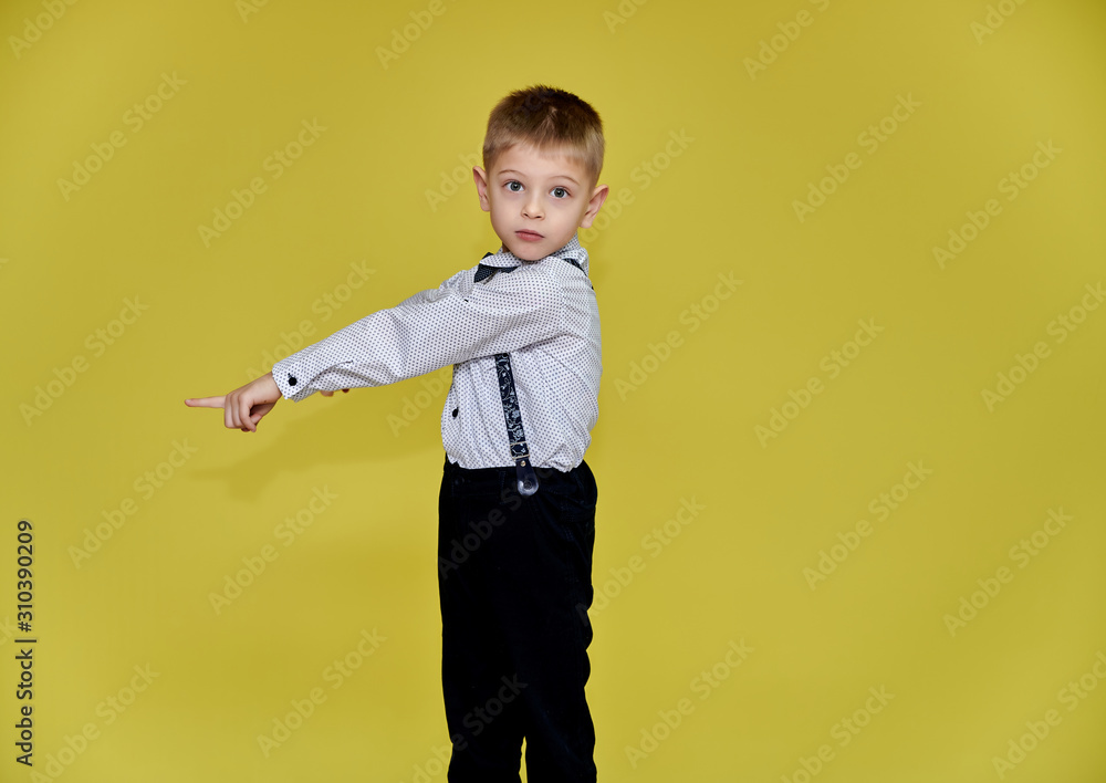 Portrait of a cute boy 10 years old schoolboy on a yellow background in trousers and a shirt. Standing right in front of the camera, Shows emotions, talks in different poses. Portrait of a cute boy 10 years old schoolboy on a yellow background in trousers and a shirt. Standing right in front of the camera, Shows emotions, talks in different poses.