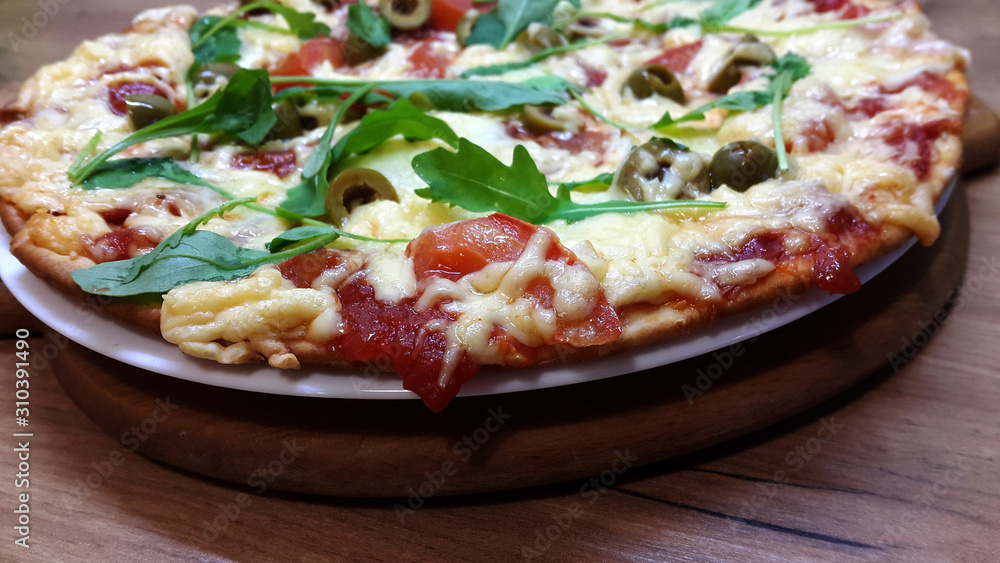 Tasty vegetarian pizza with olives, arugula, mozzarella and cherries on a wooden table. Tasty vegetarian pizza with olives, arugula, mozzarella and cherries on a wooden table.
