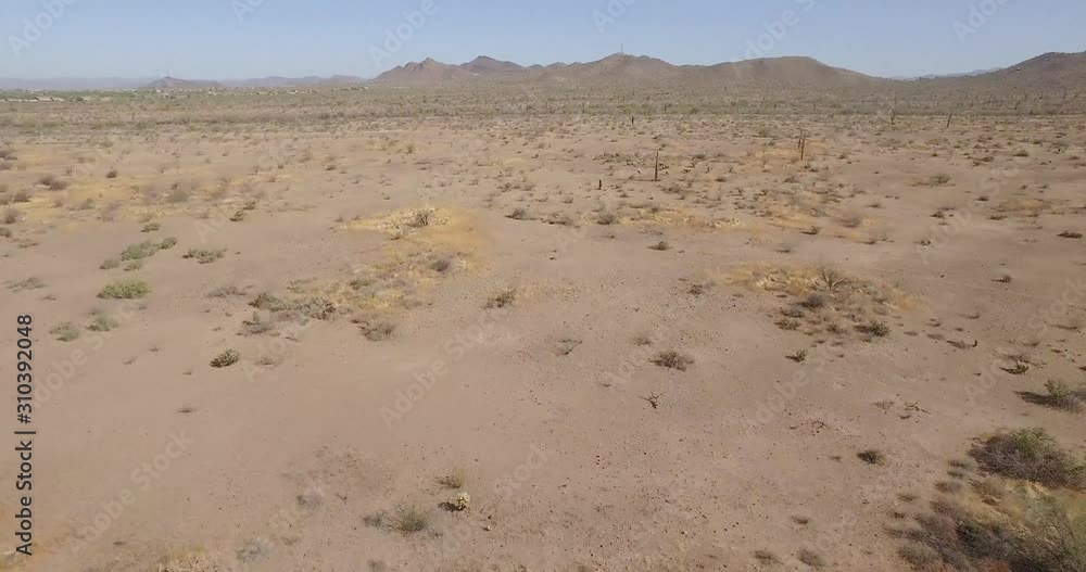 Drone glide over a hot arid desert landscape in Arizona with view of mountains in the background Drone glide over a hot arid desert landscape in Arizona with view of mountains in the background