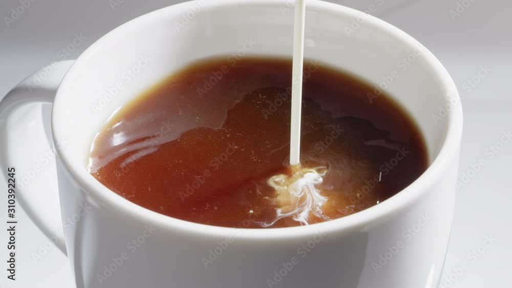 Adding cream to a cup of coffee Adding cream to a cup of coffee