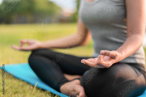 Asian woman meditating and sit in the lotus pose at park, Healthy and Yoga Concept,Mind-body improvements concept, Selective focus, Copy space.