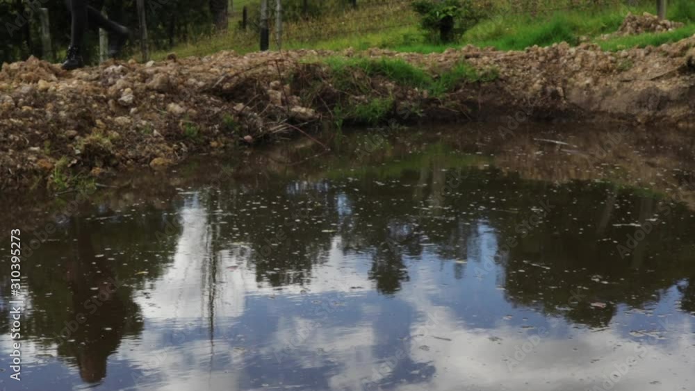 The reflection of a woman walking from right to left in a dirty water hole. Static The reflection of a woman walking from right to left in a dirty water hole. Static