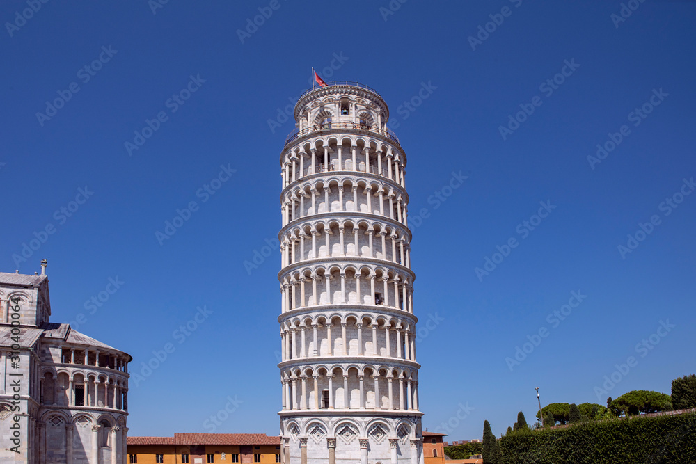 Leaning Tower of Pisa famous landmark with surrounding buildings on the square. Blue sky, summertime. Tuscany, Italy