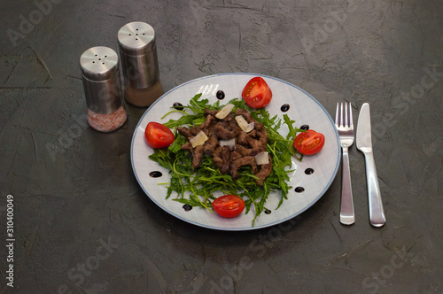 Tasty and juicy grilled meat arugula, cheese, tomato sauce and spices on a dark gray concrete background, top view