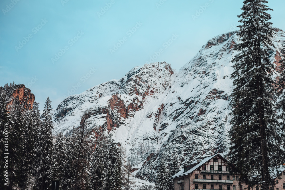 Italian alps in winter, mountains covered in snow during sunrise time, forest trees in winter. Italian alps in winter, mountains covered in snow during sunrise time, forest trees in winter.