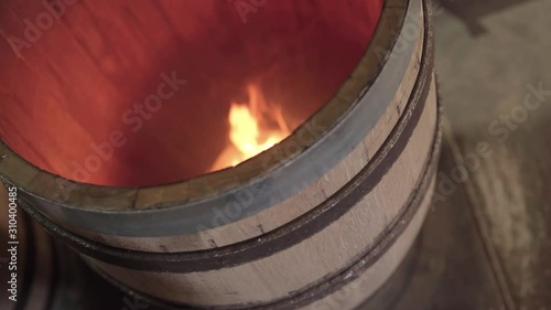 Wooden barrel turning on turntable during charring, static close up