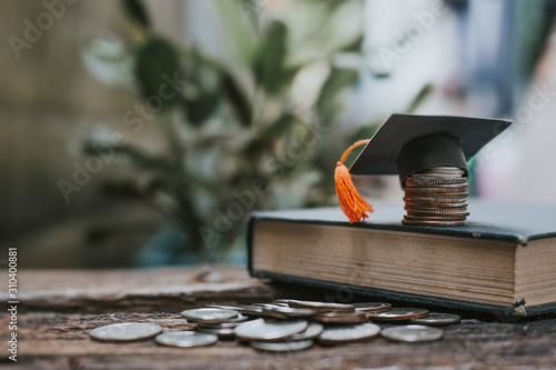 Saving money financial concept, congratulations graduates cap on top of the money with book.