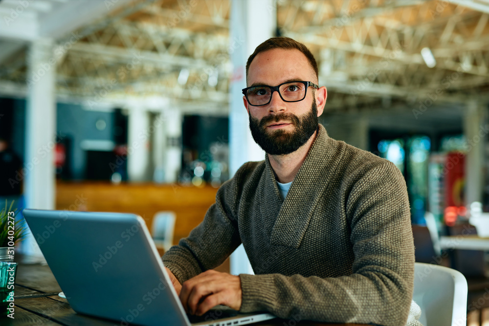 Attractive bearded man working on laptop in a cafe Attractive bearded man working on laptop in a cafe