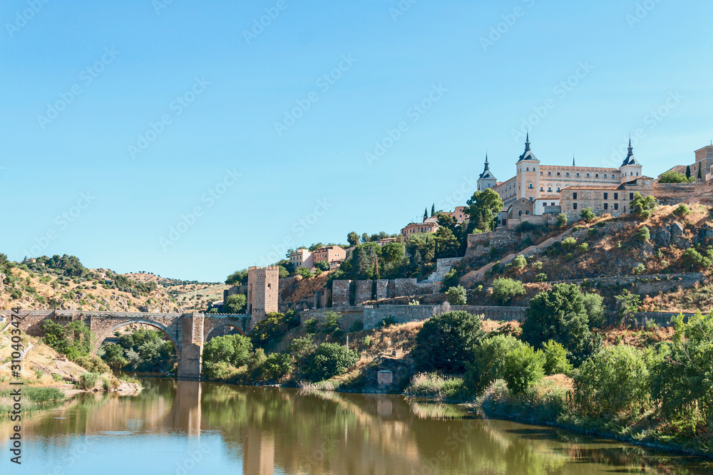 view from the river bank on the fortress wall and castles of the ancient Spanish city of Toledo