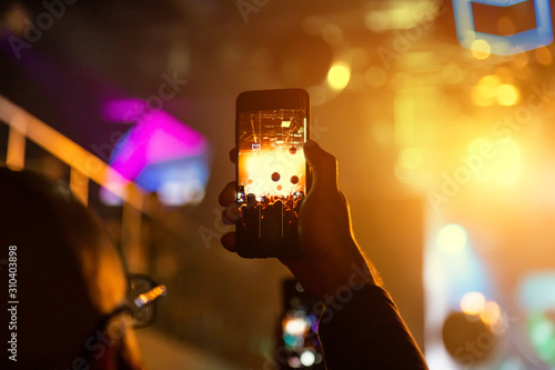 Viewer shoot video on a smartphone at a concert.