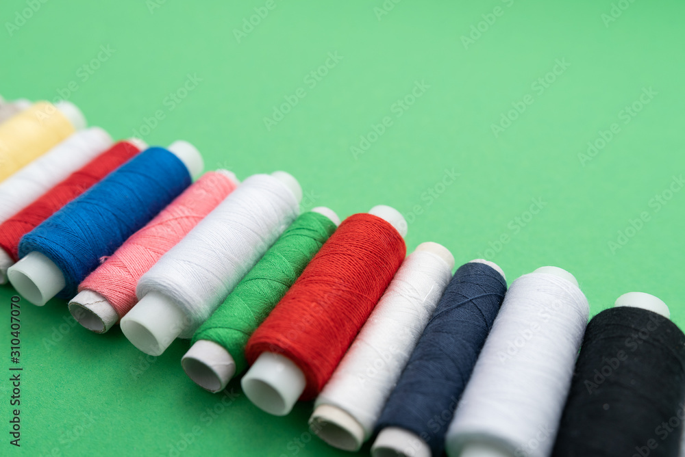colored sewing threads on green background colored sewing threads on green background