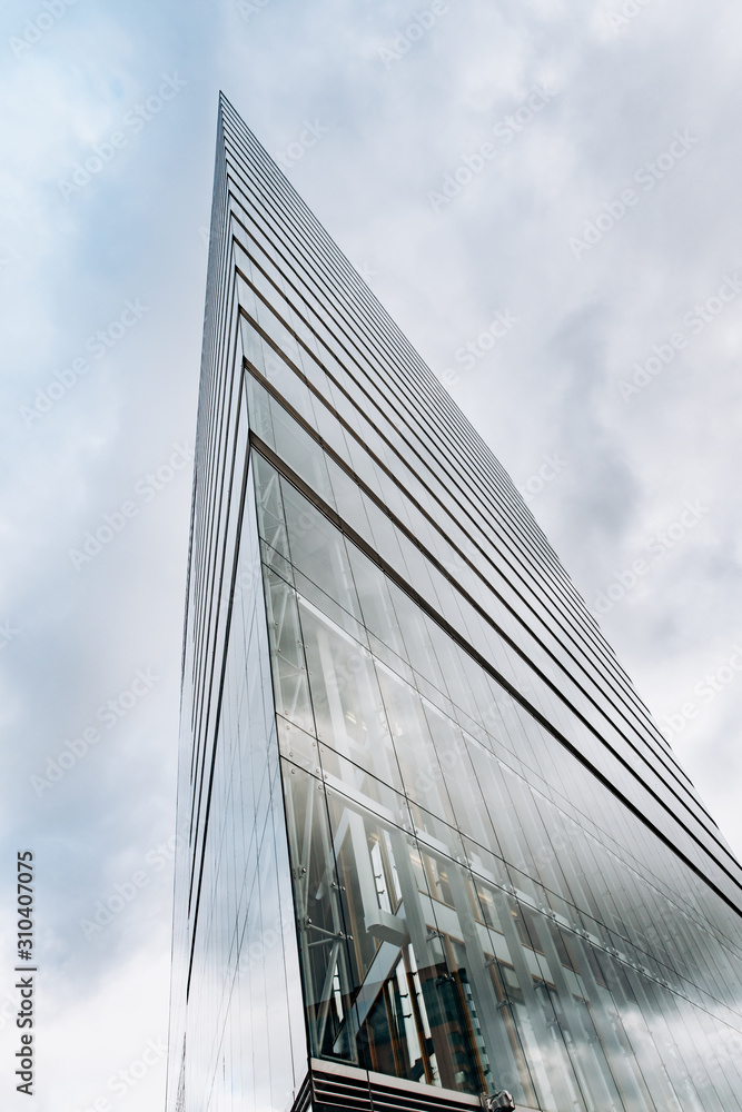 Naklejka premium Dramatic view of skyscrapers against cloudy sky. View of the skyscraper from below