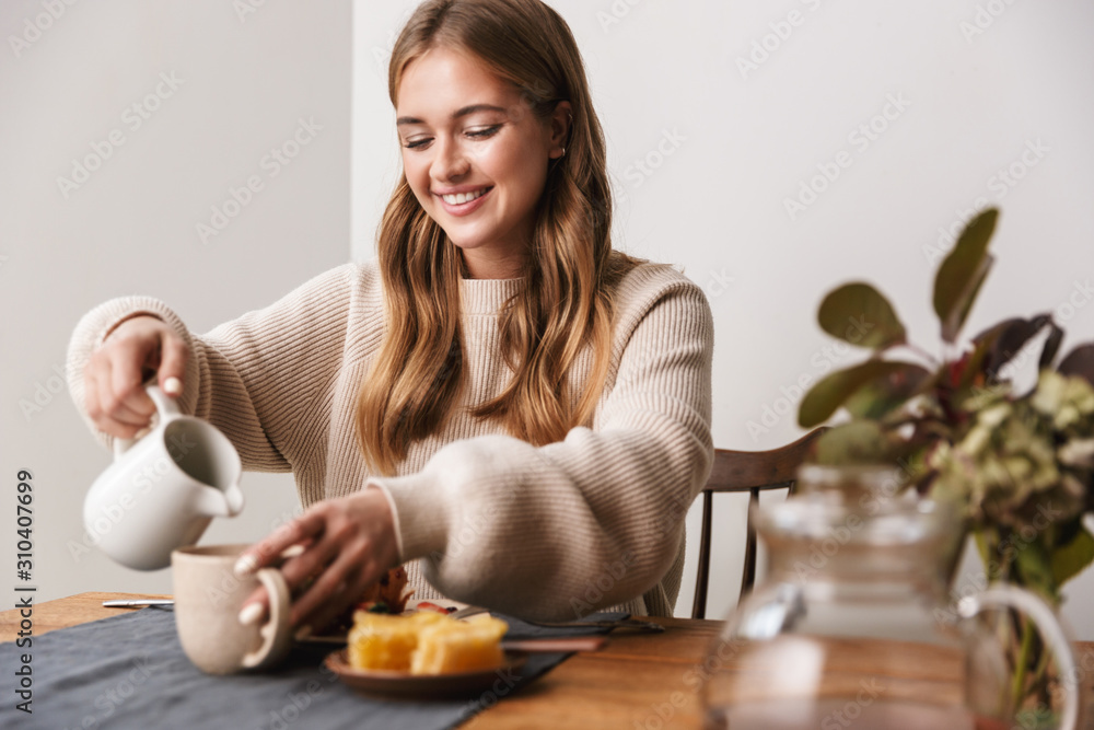 Image of happy caucasian woman drinking tea while having breakfast Image of happy caucasian woman drinking tea while having breakfast