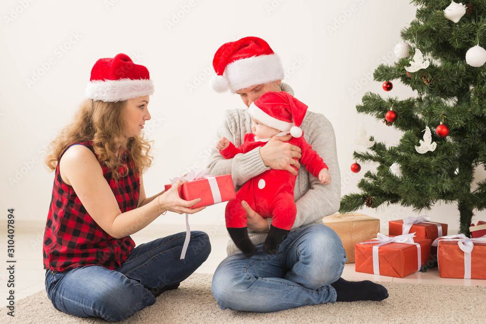 Fototapeta premium Happy couple with baby celebrating Christmas together at home.