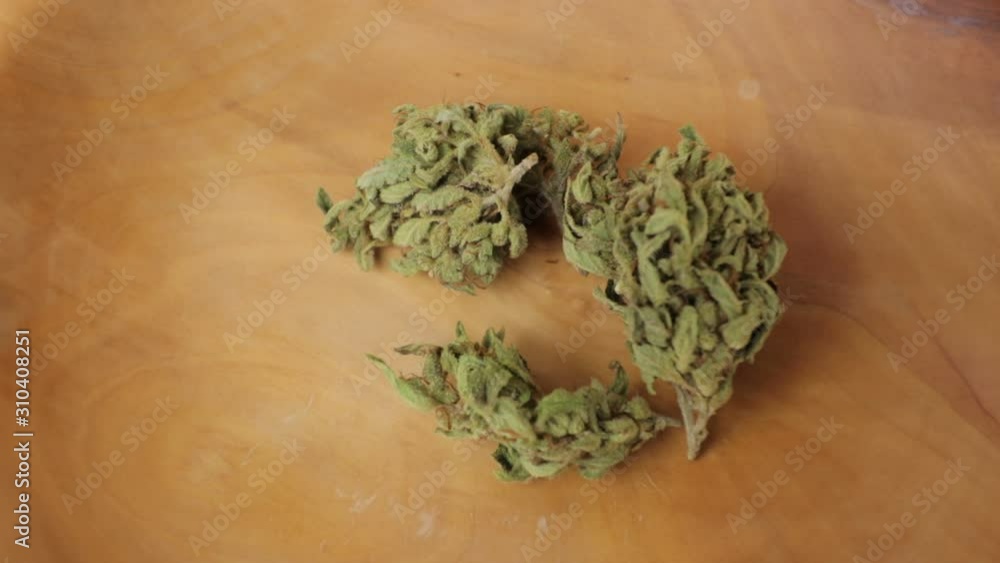 Slide and pan around sativa and indica weed buds on the wooden plate. CBD, THC illustration footage. Wide, closeup Slide and pan around sativa and indica weed buds on the wooden plate. CBD, THC illustration footage. Wide, closeup